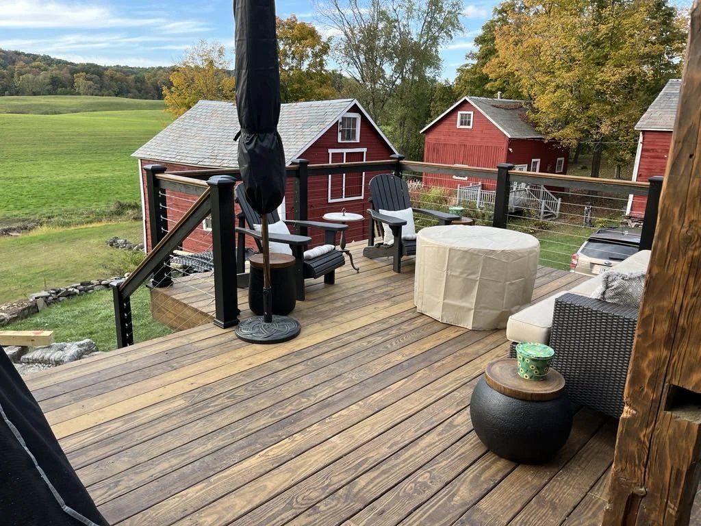 Deck with cable railing and Adirondack chairs overlooking a farm