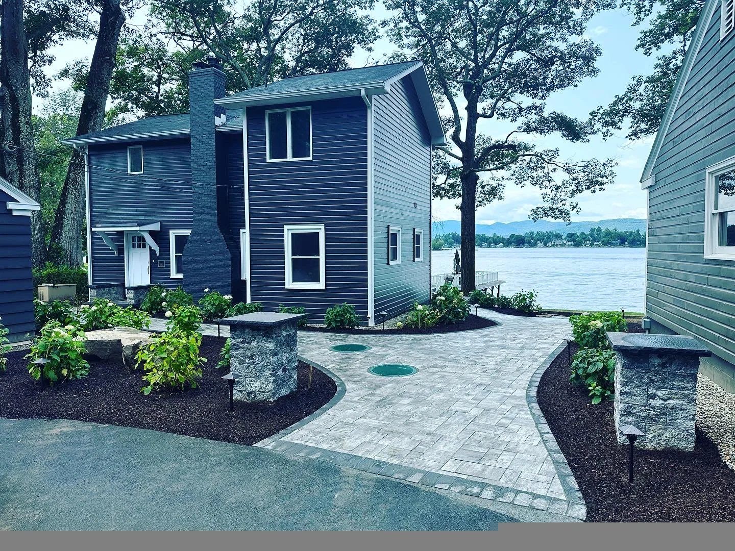 Paver walkway with stone pillars at a waterfront home